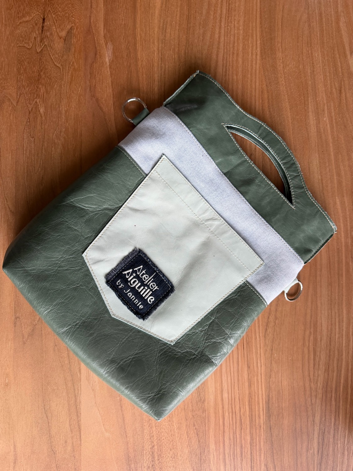 Olijfgroene leren tas met crèmewit zakje en Atelier Aiguille label